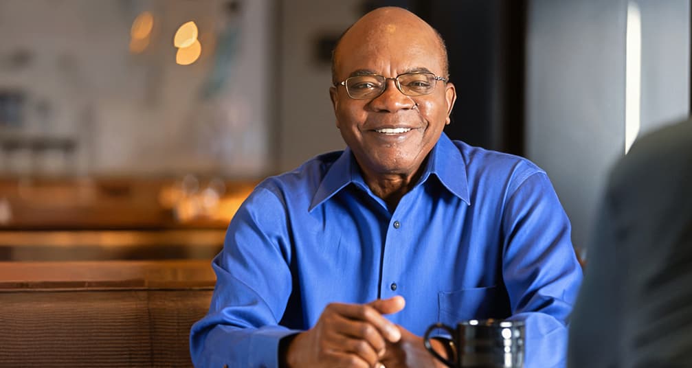 Appolos, a Hizentra patient advocate smiling sitting at a table