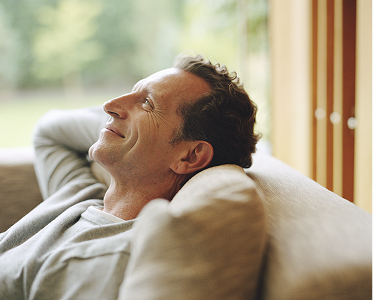 A man reclining on a couch feeling content