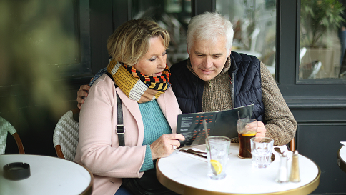 A couple stting at an outdoor table reading a Hizentra brochure