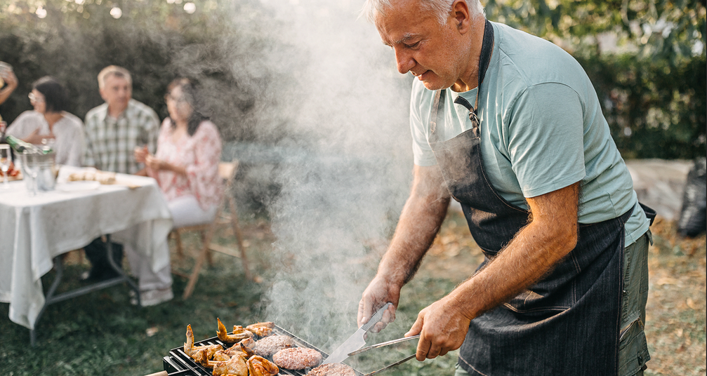 A man prepares barbeque on the grill outside