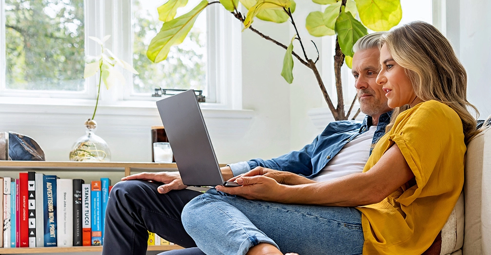 Couple sitting next to each other researching on a laptop