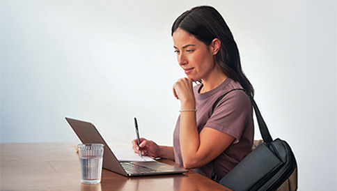 Woman looking at her laptop while holding a pen