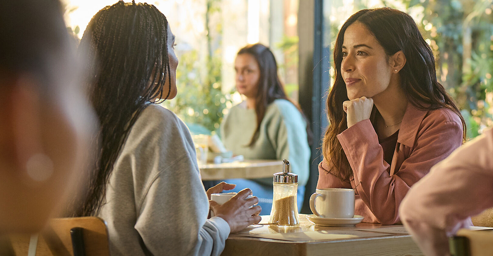 Woman in conversation sitting a a table smiling and enjoying a drink