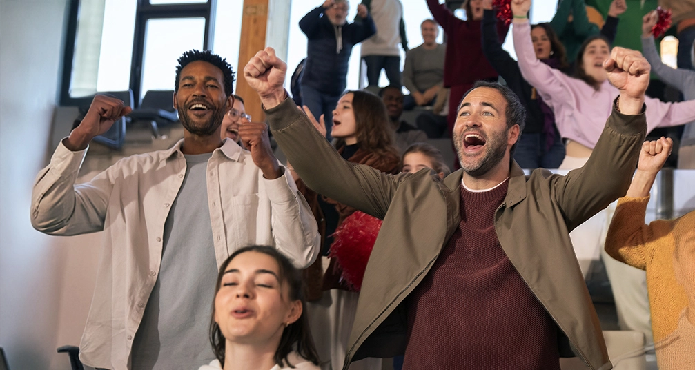 Exicted people cheering in an audience at a game